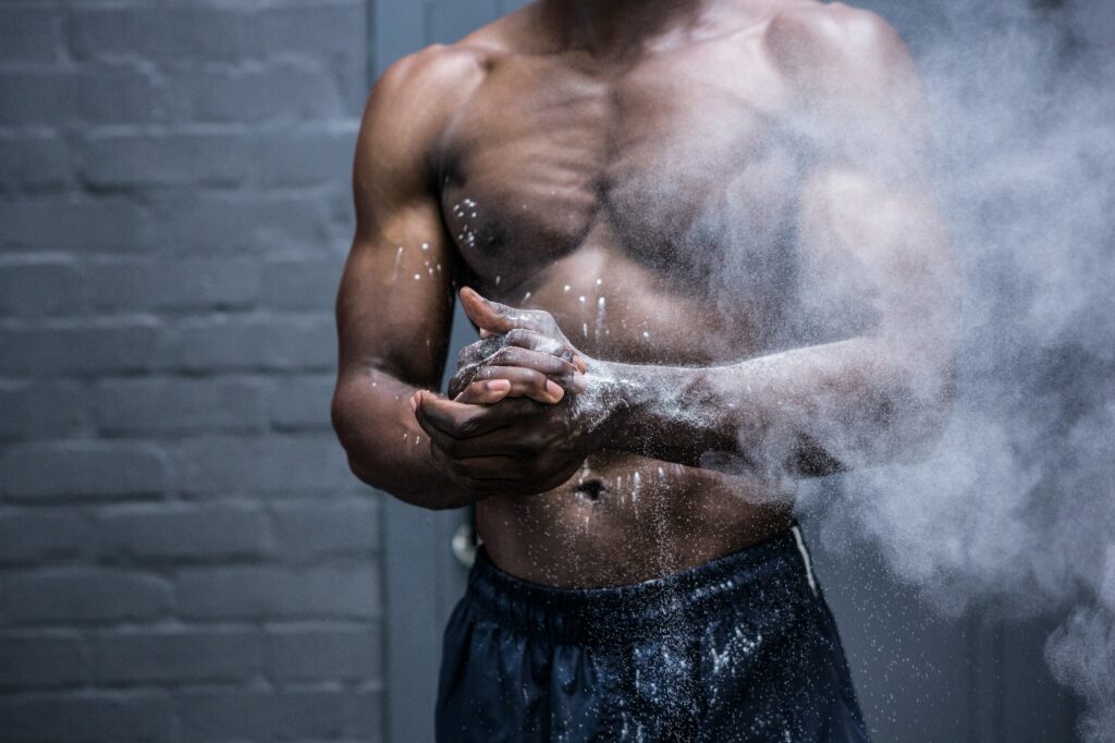 Young Bodybuilder shaking Chalk off his hands in the crossfit gym