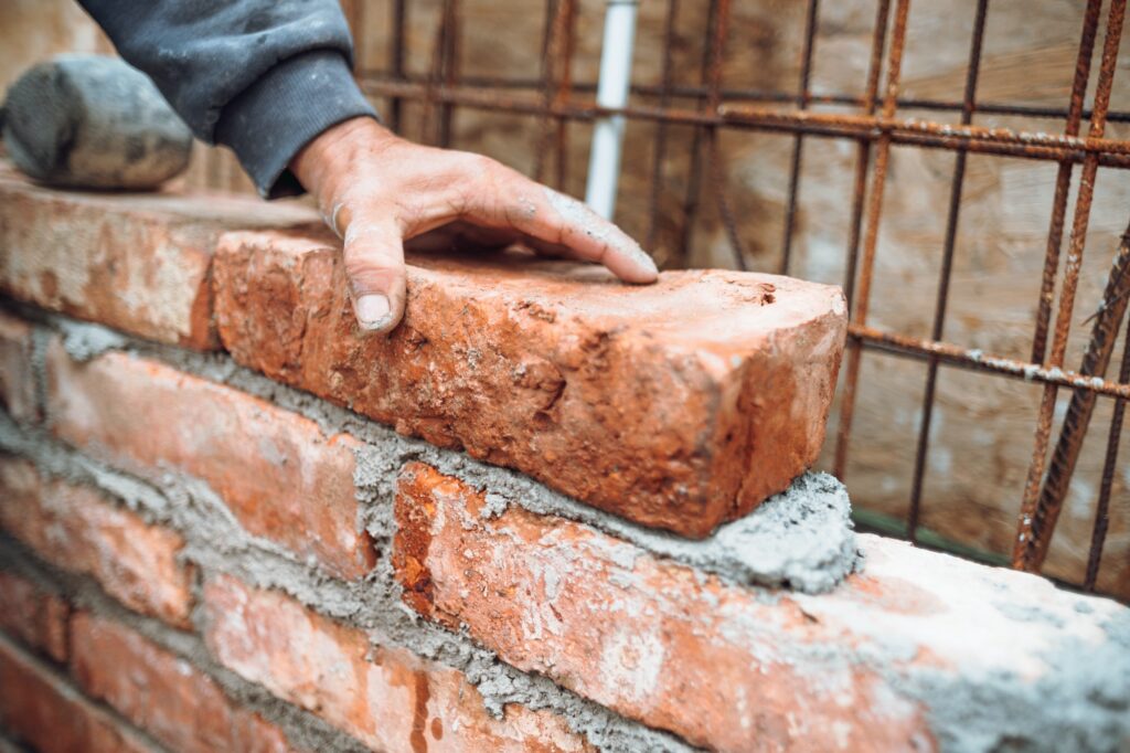 worker laying bricks and building walls on construction site. Detail of hand adjusting