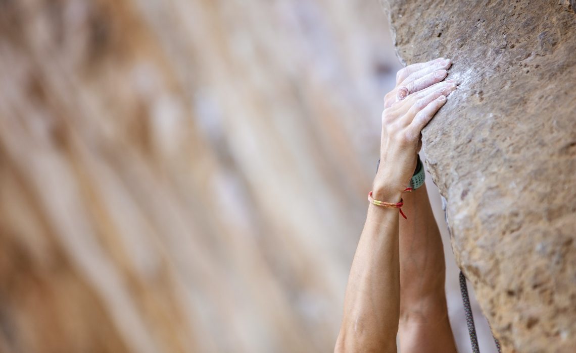 Close up climber’s hands on a cliff Close up climber's hands on a cliff